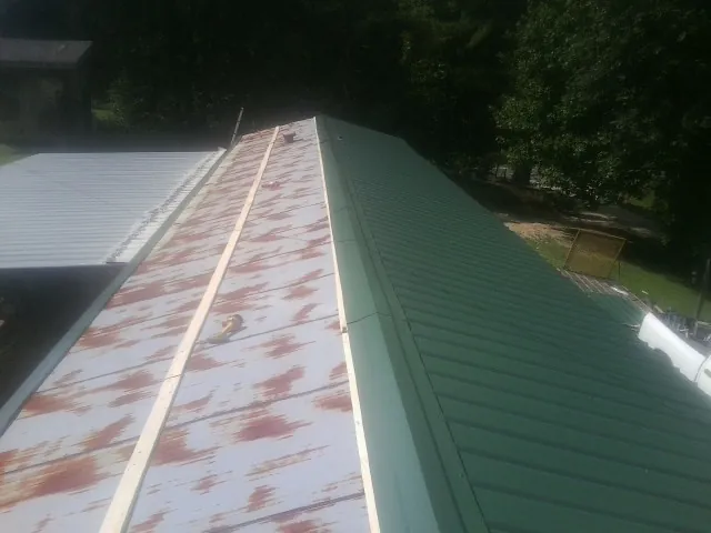 Old rusted panels beside newly installed green metal roofing — Wind Damage Roof Repair by Roofing Brothers in Mineral Wells
