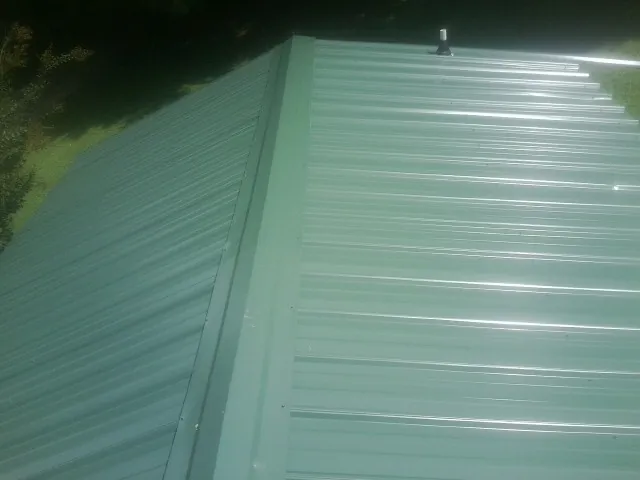 New green metal panels meeting at the ridge of a roof — Flat Roof Repair work by our crew in Mineral Wells